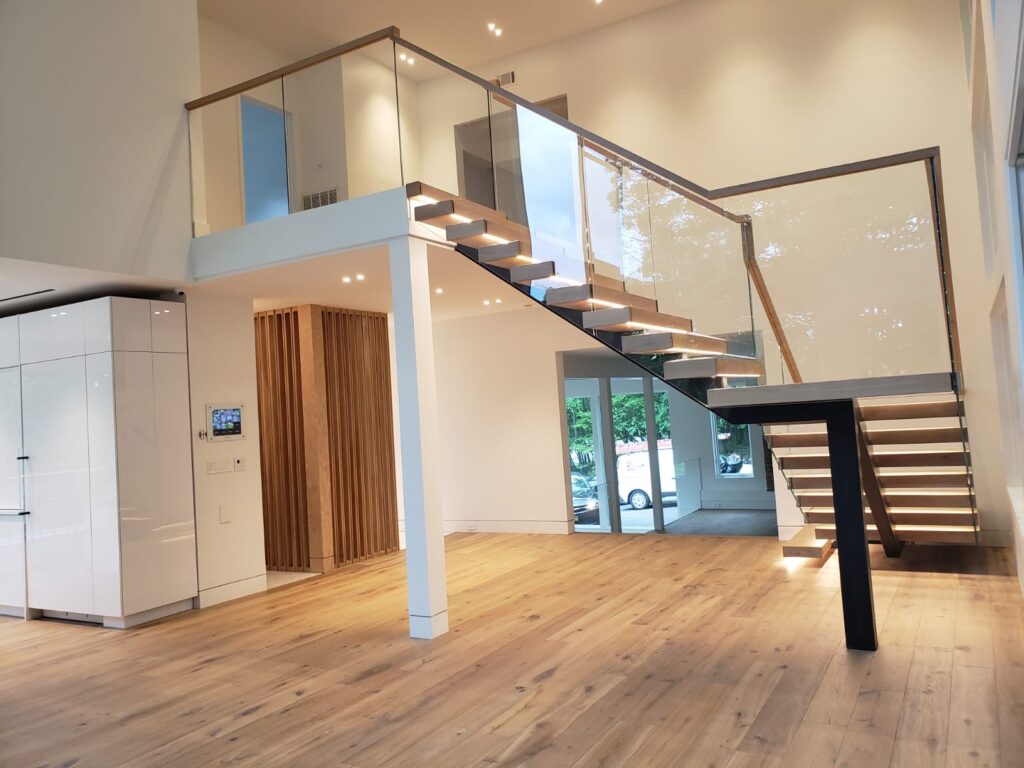 Bright living area with an open staircase featuring wooden steps and a sleek, black support beam.