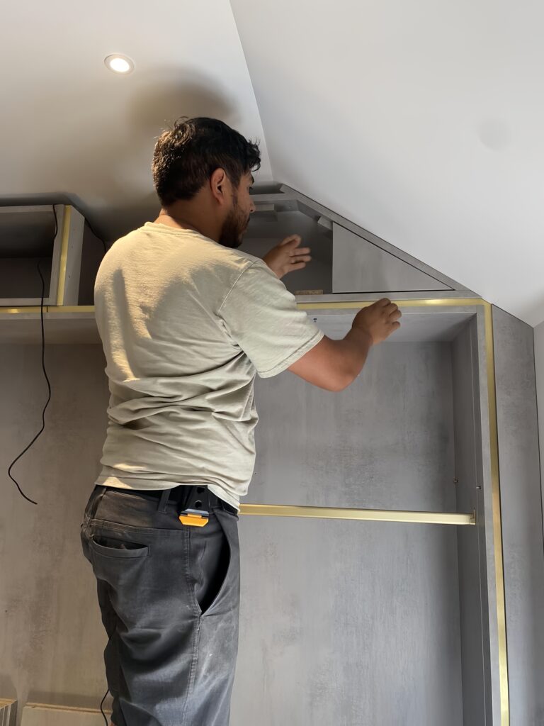 Carpenter precisely installing custom cabinetry in a modern home interior.