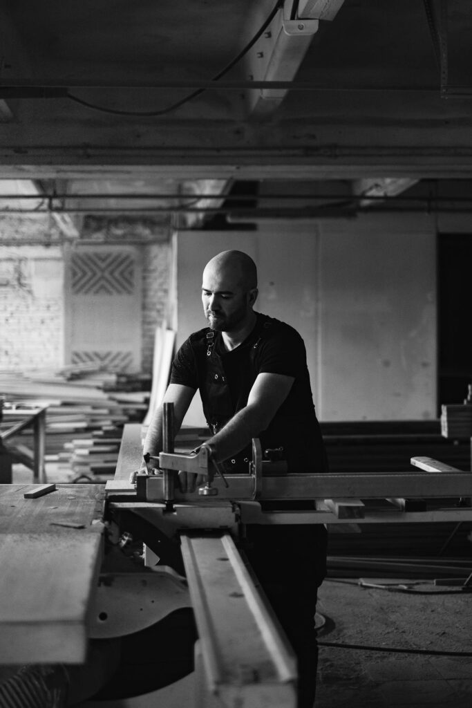 Skilled craftsman operating a table saw in a woodworking workshop, focused on precisely cutting a piece of wood.