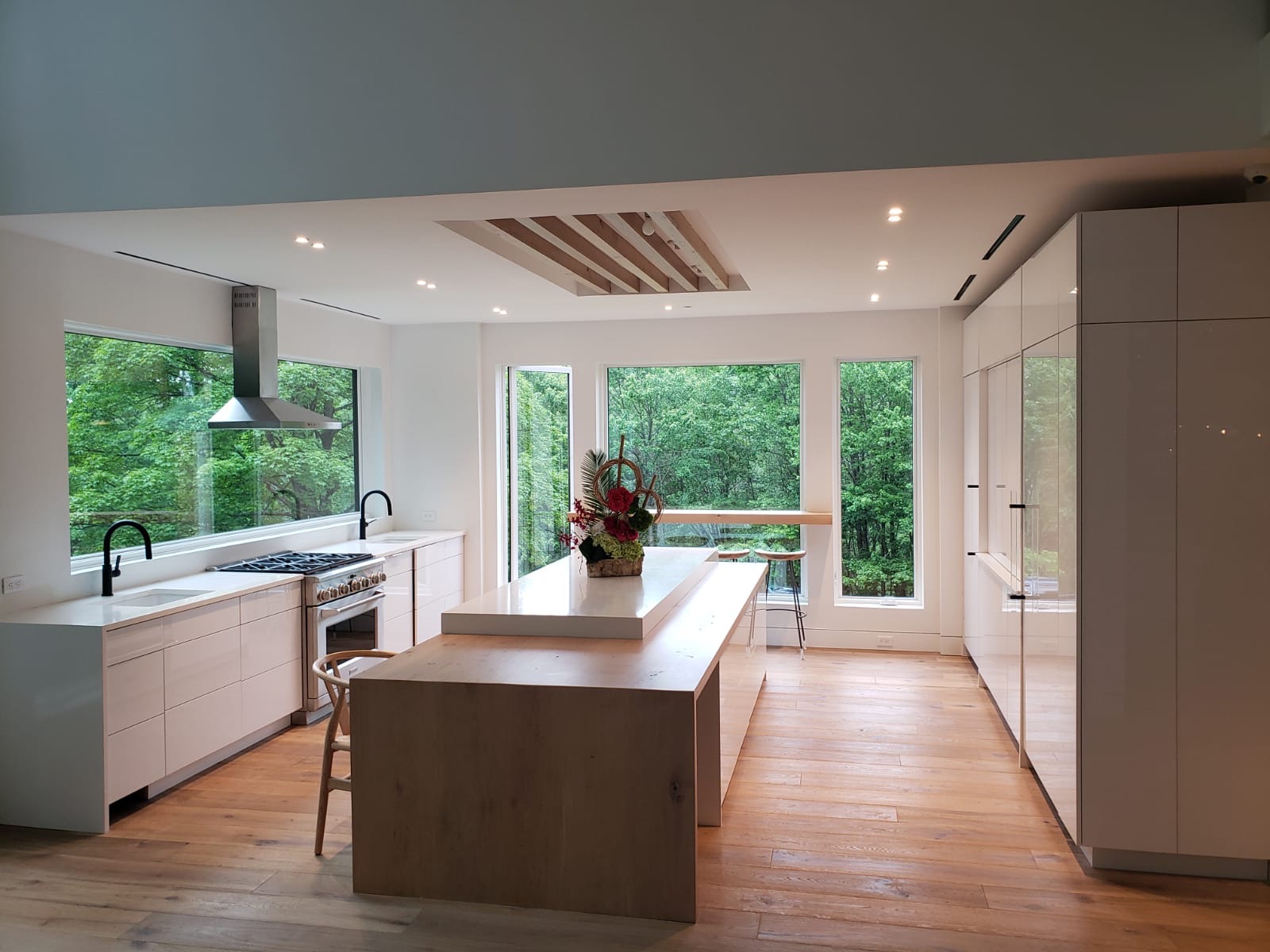 Spacious kitchen interior with wooden flooring, featuring a large island and sleek white cabinetry.