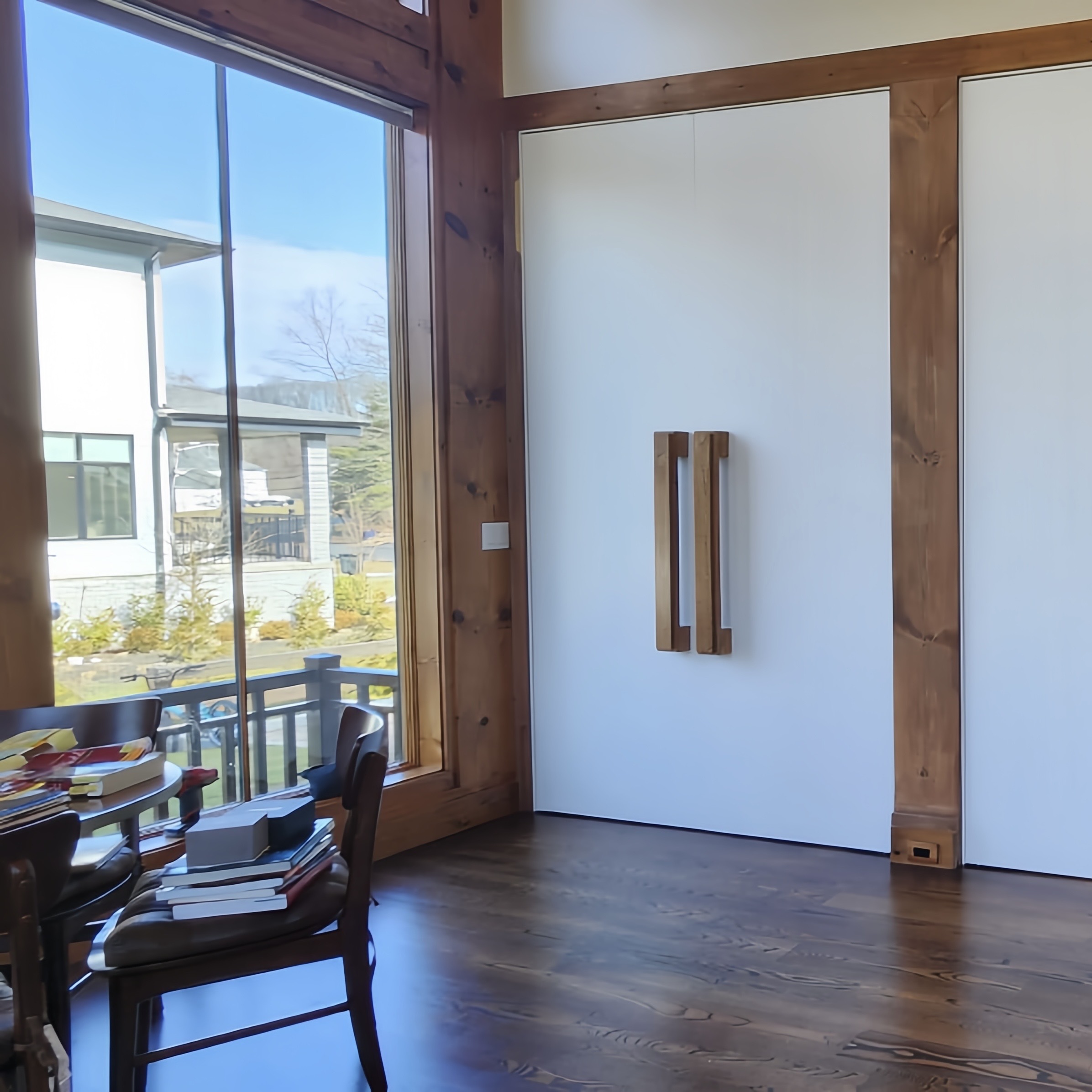 Cozy corner of a modern home with large windows, wooden beams, and a sliding barn door.