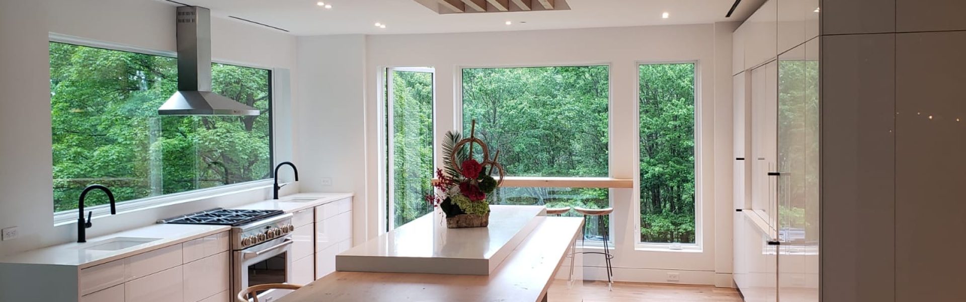 Spacious kitchen interior with wooden flooring, featuring a large island and sleek white cabinetry.